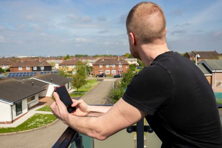 Man holding phone looking out at houses